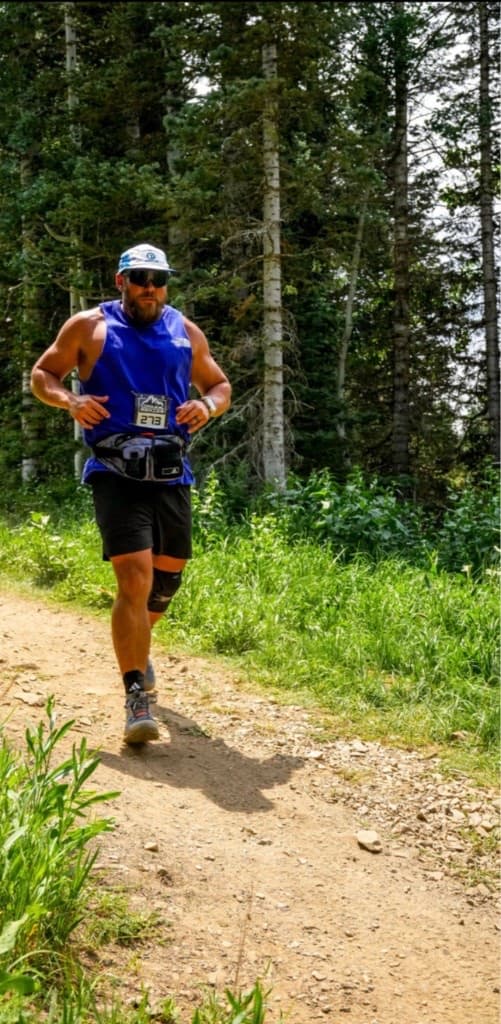 Nick trail running a mountain race in a blue tank top