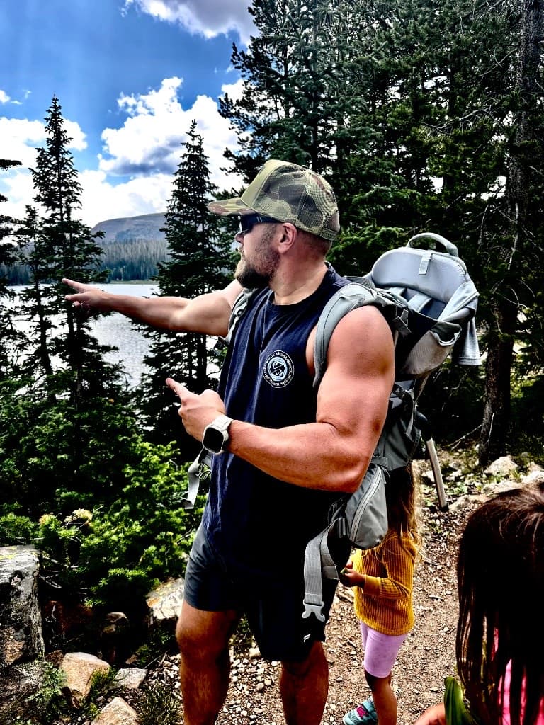 Nick pointing out a mountain lake on a forest trail with his kids
